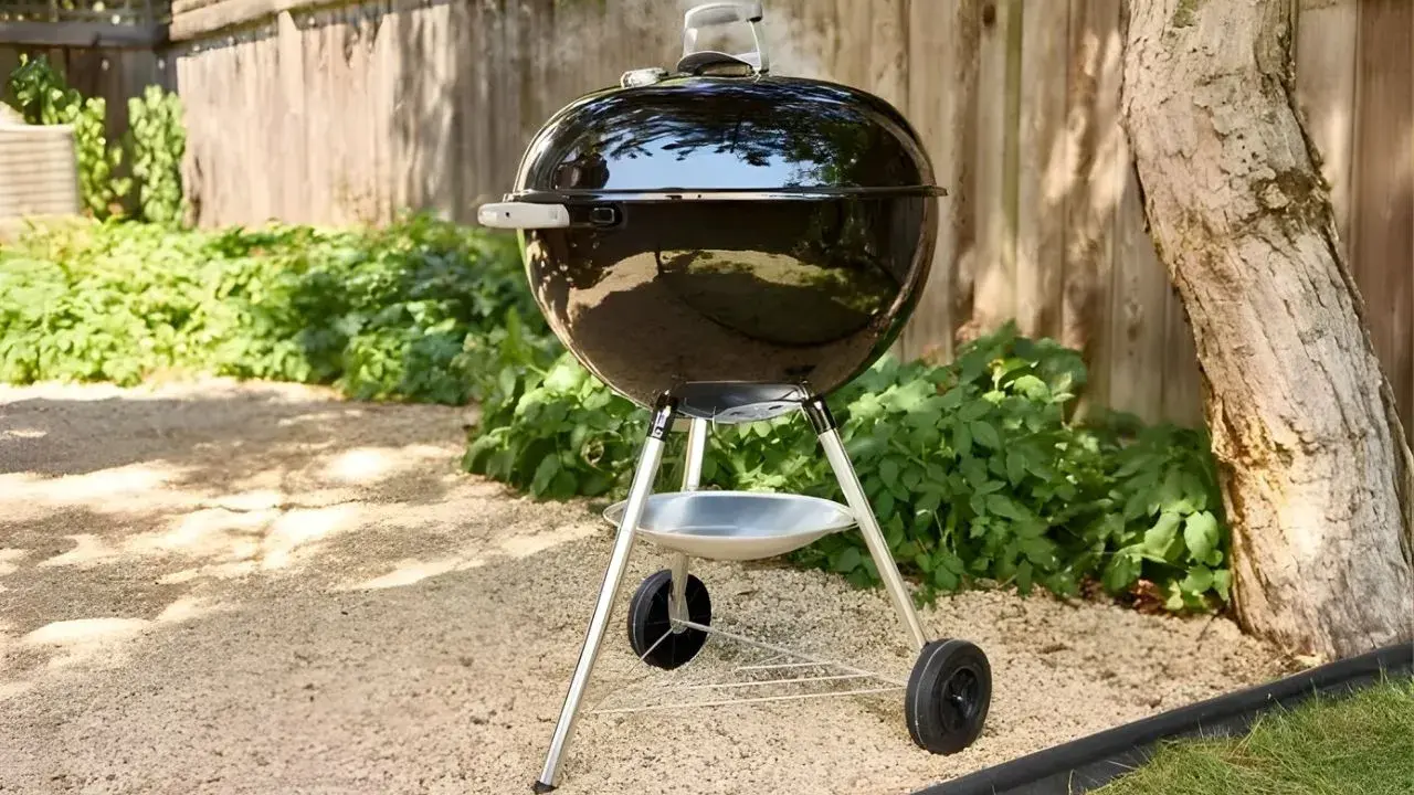 Un barbecue noir fumant, prêt à faire griller de bonnes choses dans le jardin. L'été arrive, il est temps de faire un barbecue !