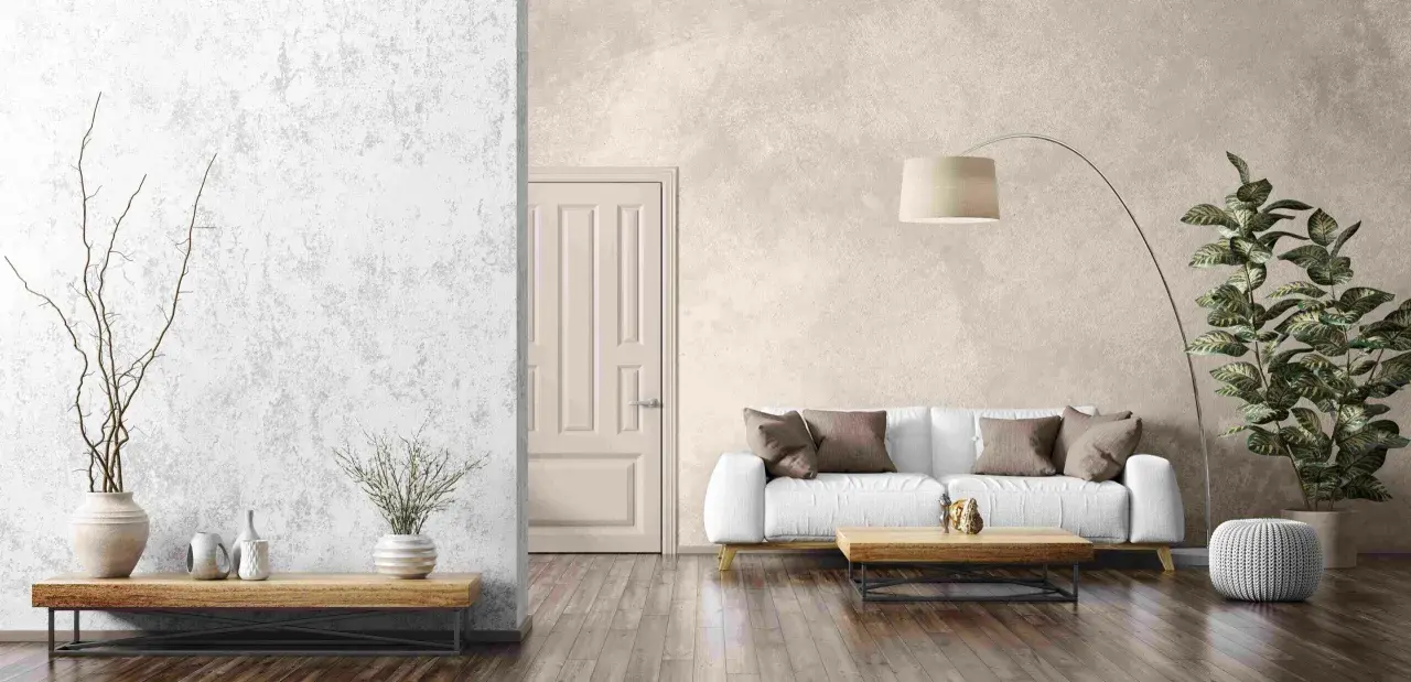 Salon moderne avec un canapé blanc, une table basse en bois et un grand pot de fleurs. Le mur de fond présente un bel **effet enduit décoratif** texturé.