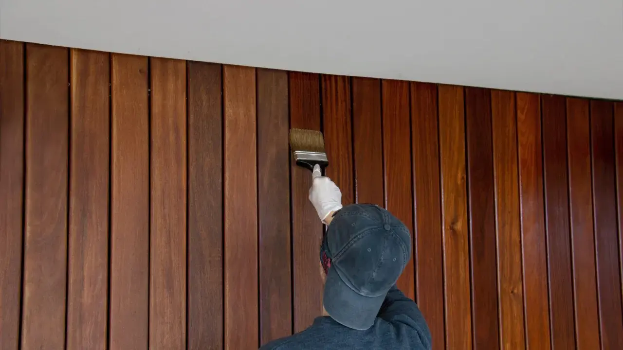 Application d'une finition sur un lambris en bois. Le résultat avant/après est saisissant, révélant la beauté naturelle du bois.
