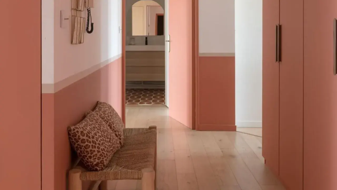 Banc en rotin avec coussins léopard, murs bicolores corail et blanc, portes roses. Une belle idée déco couloir moderne.