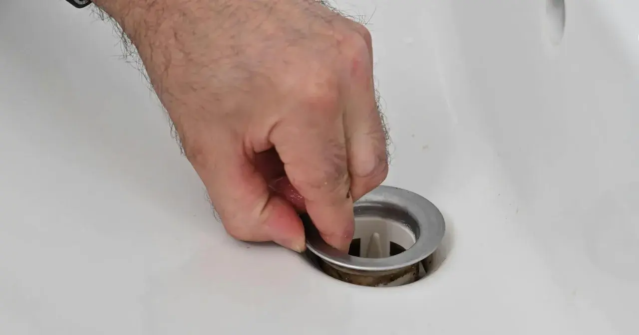 Main tenant la bonde du lavabo pour la changer.