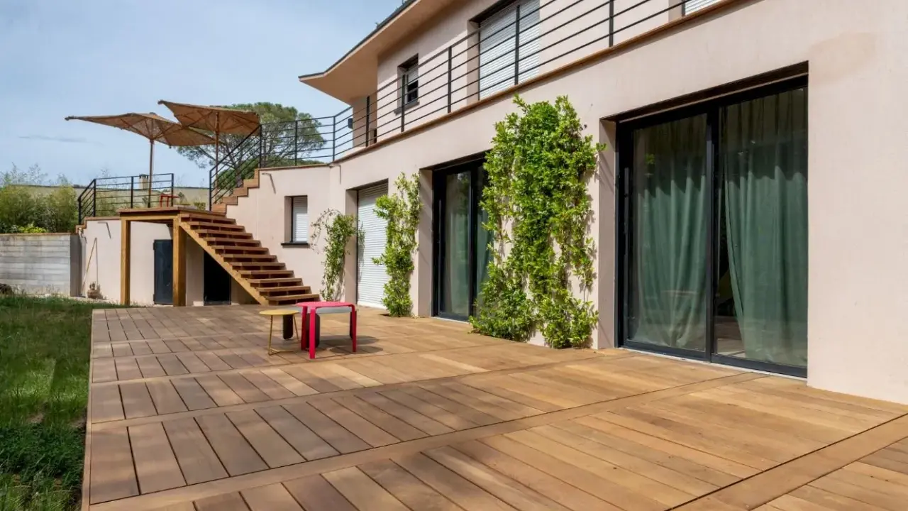 Grande terrasse en bois, une dalle terrasse directement sur terre, menant à un escalier extérieur.