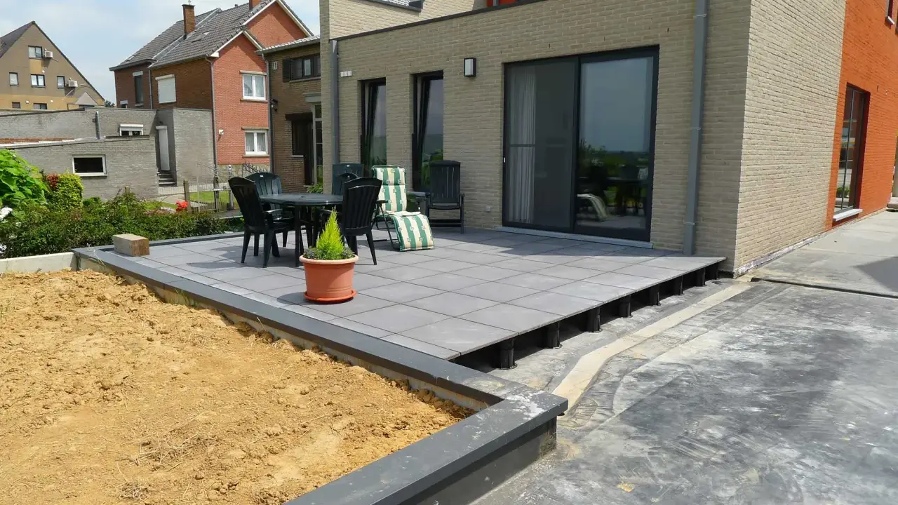 Terrasse avec dalles grises sur plots, prête à accueillir une dalle béton. Table et chaises sur le côté.