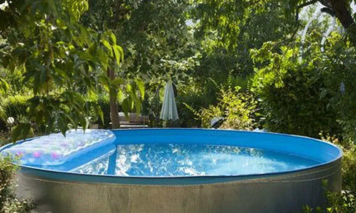 Installation piscine hors sol terminée, prête pour les baignades estivales. Un matelas gonflable flotte sur l'eau bleue.