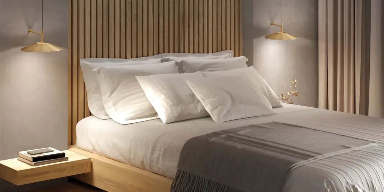 Lit et sa tête de lit en bois, oreillers blancs, lampe dorée. Une ambiance douce pour la deco de chambre.