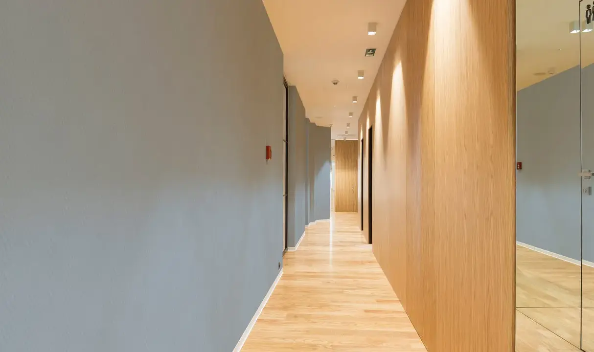 Couloir moderne avec un mur bleu texturé, un mur en bois clair et un sol en parquet. Le mur de gauche, en fibre de verre, est d'un bleu doux.