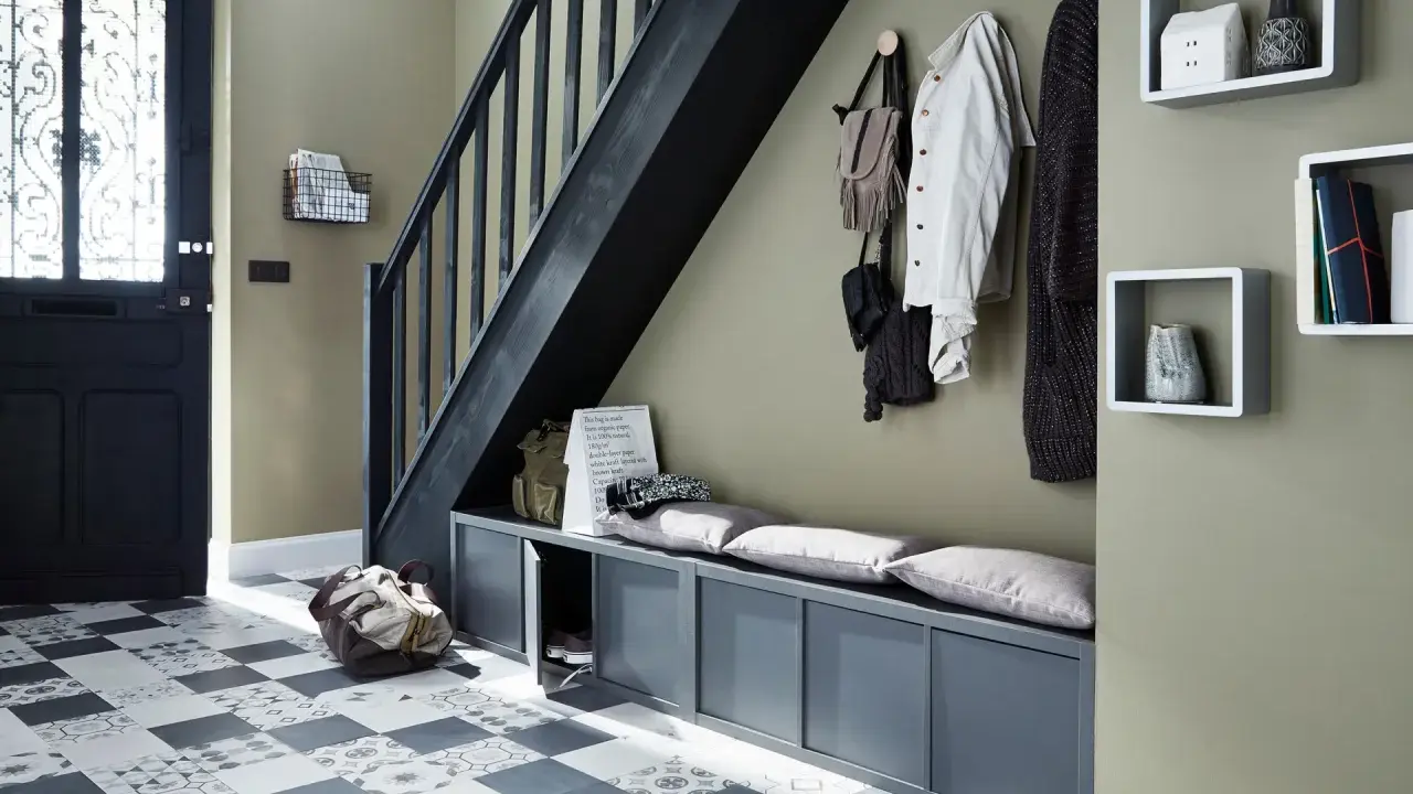 Escalier moderne avec une couleur tendance, banc de rangement gris, porte d'entrée noire et sol à motifs.