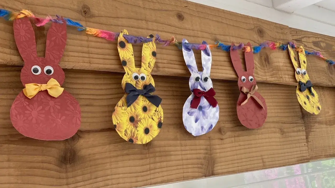 Guirlande de lapins colorés, déco de Pâques à faire soi-même avec récup. Des lapins en papier aux motifs variés, ornés de nœuds et d'yeux mobiles, suspendus à une ficelle multicolore.