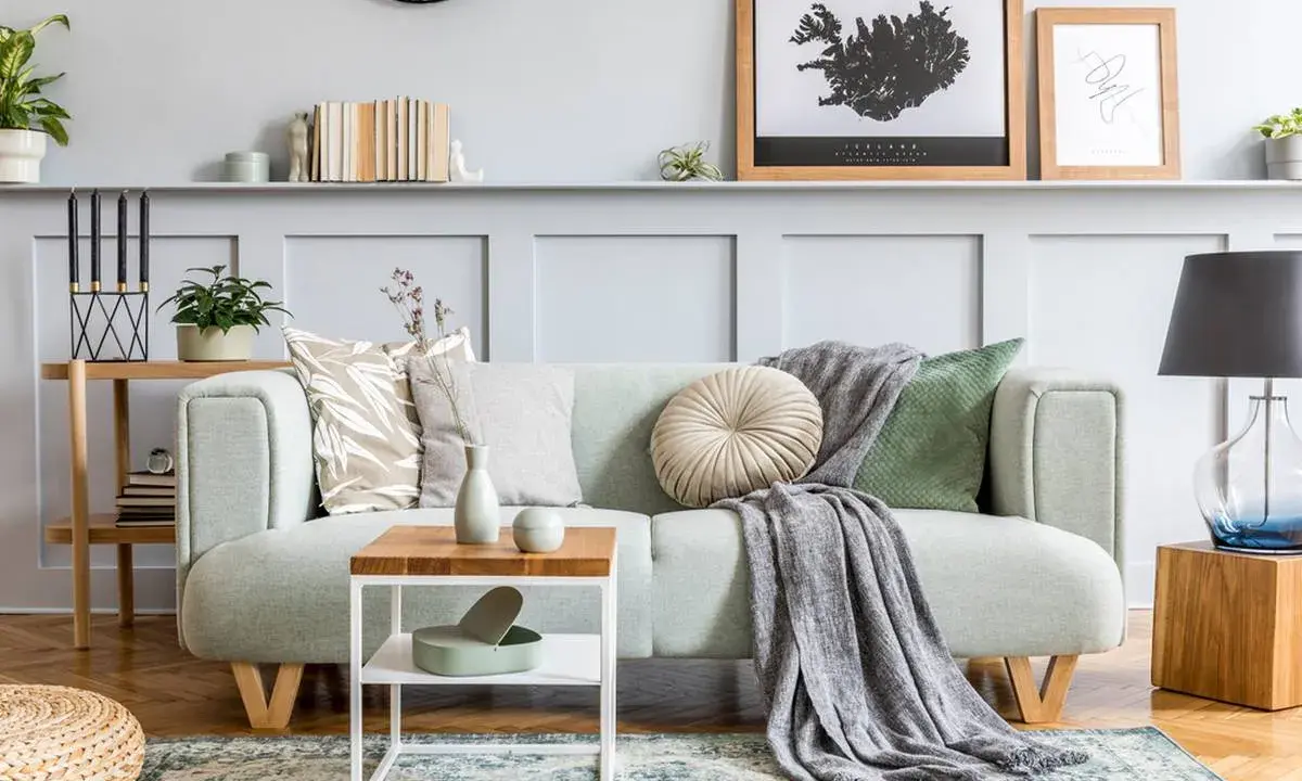 Un plaid gris drapé sur un canapé vert menthe, ajoutant une touche cosy. Idée pour comment mettre un plaid sur un canapé avec style.