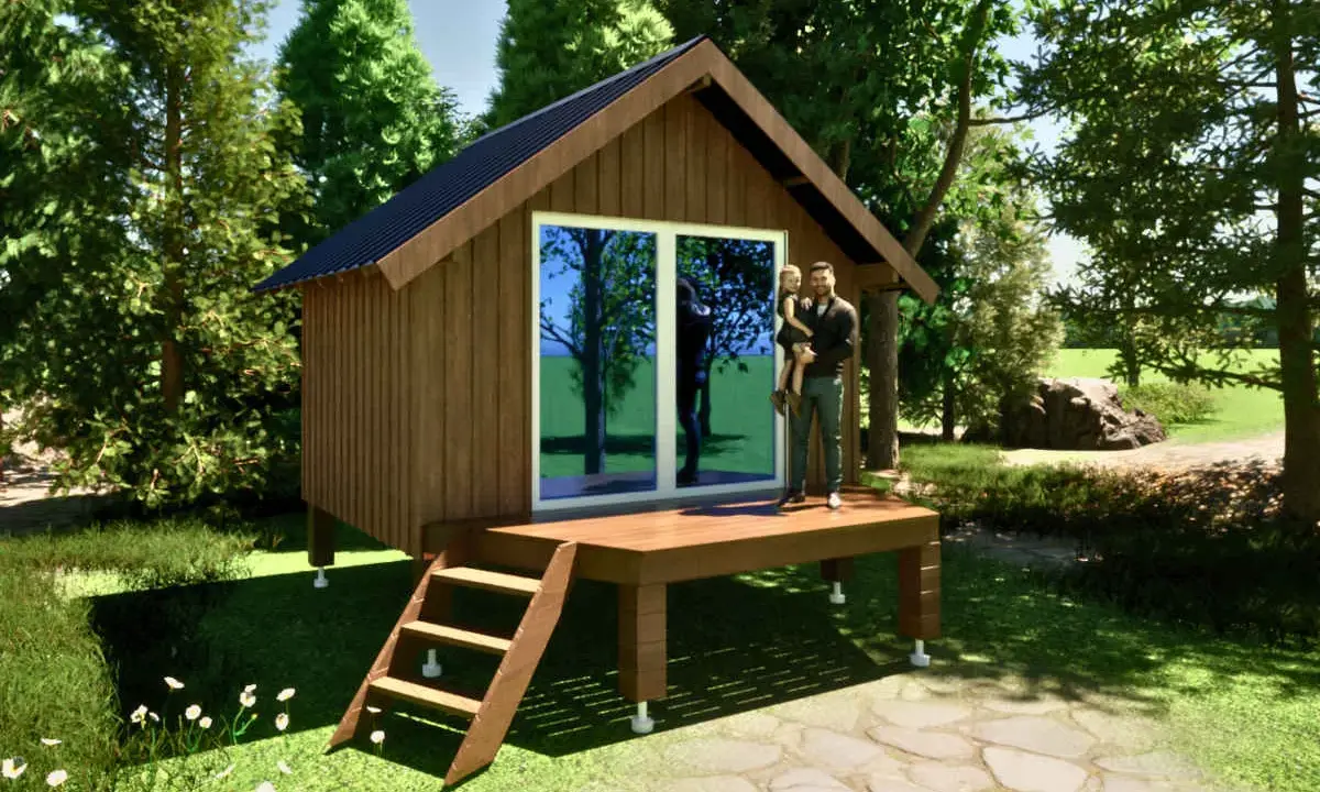 Un homme porte sa fille sur la terrasse d'un abri de jardin sur plot, entouré de verdure.