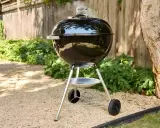 Un barbecue noir fumant, prêt à faire griller de bonnes choses dans le jardin. L'été arrive, il est temps de faire un barbecue !