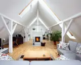 Salon aménagé sous les combles avec cheminée, canapés confortables et poutres apparentes. Le cout d'aménagement combles est bien rentabilisé.