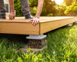 Construction d'une terrasse en bois sur pelouse. Des mains ajustent les lames d'une nouvelle terrasse sur des supports.