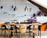 Une cuisine ouverte sur salle à manger avec un îlot central, des chaises en bois et des suspensions cuivrées.