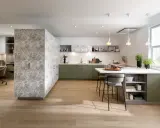 Une cuisine moderne avec des armoires vert sauge et un mur à motifs floraux. La peinture salle à manger 2 couleurs crée un espace chaleureux et invitant.