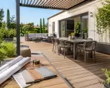 Aménagement d'une **terrasse en L** moderne avec salon extérieur, table à manger et matériaux de construction.