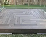Une belle terrasse bois sur plot béton, avec un motif en chevrons élégant et une balustrade en verre moderne.