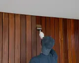 Application d'une finition sur un lambris en bois. Le résultat avant/après est saisissant, révélant la beauté naturelle du bois.