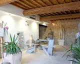 Salon moderne avec poutre apparente. Deux fauteuils en bois, une table, des plantes et des statues ornent cet espace chaleureux.