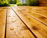 Gouttes d'eau sur une terrasse en bois fraîchement traitée, montrant la protection efficace du bois.