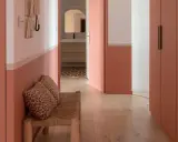 Banc en rotin avec coussins léopard, murs bicolores corail et blanc, portes roses. Une belle idée déco couloir moderne.
