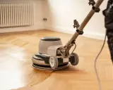 Polissage d'un parquet ancien avec une ponceuse. La rénovation redonne tout son éclat au bois.