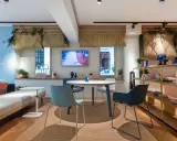 Ambiance lumineuse et colorée pour une idée décoration bureau professionnel. Canapés, table ronde, étagères et plantes créent un espace accueillant.