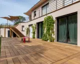 Grande terrasse en bois, une dalle terrasse directement sur terre, menant à un escalier extérieur.