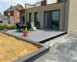 Terrasse avec dalles grises sur plots, prête à accueillir une dalle béton. Table et chaises sur le côté.
