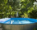 Installation piscine hors sol terminée, prête pour les baignades estivales. Un matelas gonflable flotte sur l'eau bleue.
