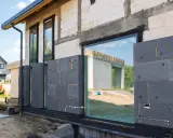 Panneaux de polystyrène gris fixés sur un mur de blocs de béton pour l'isolation par l'extérieur d'une maison en construction.