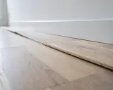 Planches de parquet gondolé, prêtes à être posées. On dirait qu'un fer à repasser a été utilisé pour les aplatir.