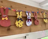 Guirlande de lapins colorés, déco de Pâques à faire soi-même avec récup. Des lapins en papier aux motifs variés, ornés de nœuds et d'yeux mobiles, suspendus à une ficelle multicolore.