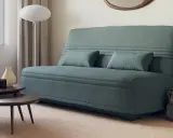 Canapé bz ou clic clac bleu canard, avec coussins, près d'une fenêtre et de tables basses. Parfait pour un petit espace.
