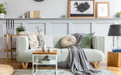 Un plaid gris drapé sur un canapé vert menthe, ajoutant une touche cosy. Idée pour comment mettre un plaid sur un canapé avec style.