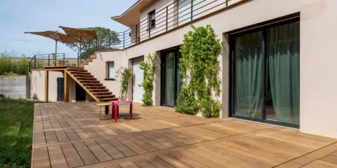 Grande terrasse en bois, une dalle terrasse directement sur terre, menant à un escalier extérieur.
