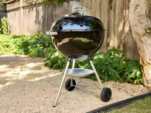 Un barbecue noir fumant, prêt à faire griller de bonnes choses dans le jardin. L'été arrive, il est temps de faire un barbecue !
