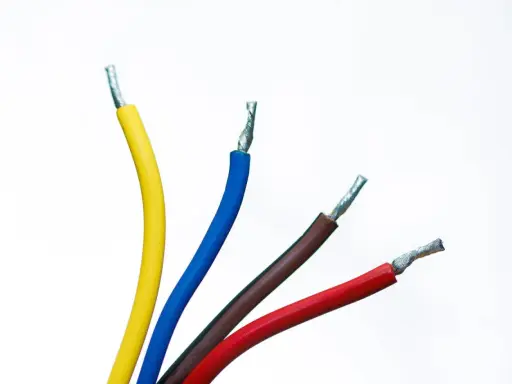 Faisceau de fils électriques colorés : jaune, bleu, marron et rouge. Un fil noir est caché parmi eux, prêt à transporter l'électricité.