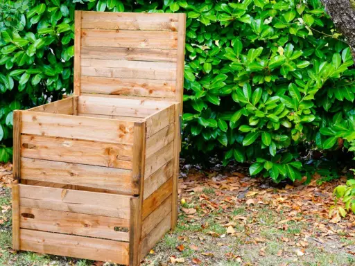 Un composteur en bois, prêt à l'emploi, est installé dans un jardin verdoyant. Idéal pour fabriquer un composteur maison.