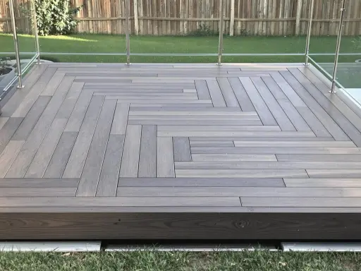 Une belle terrasse bois sur plot béton, avec un motif en chevrons élégant et une balustrade en verre moderne.