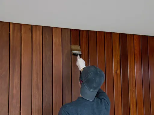Application d'une finition sur un lambris en bois. Le résultat avant/après est saisissant, révélant la beauté naturelle du bois.