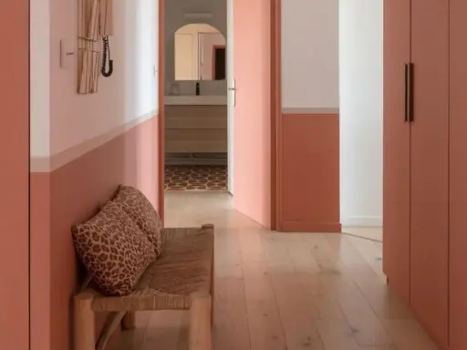 Banc en rotin avec coussins léopard, murs bicolores corail et blanc, portes roses. Une belle idée déco couloir moderne.