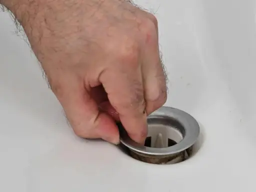 Main tenant la bonde du lavabo pour la changer.