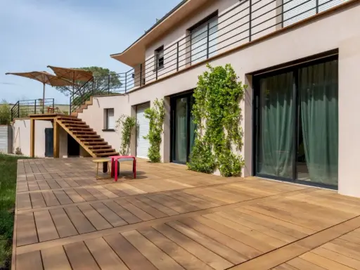 Grande terrasse en bois, une dalle terrasse directement sur terre, menant à un escalier extérieur.