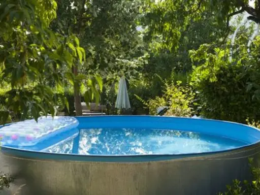 Installation piscine hors sol terminée, prête pour les baignades estivales. Un matelas gonflable flotte sur l'eau bleue.