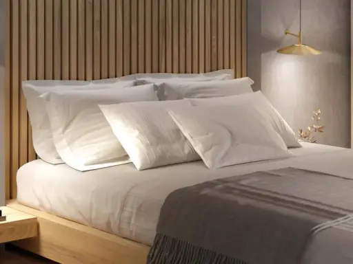 Lit et sa tête de lit en bois, oreillers blancs, lampe dorée. Une ambiance douce pour la deco de chambre.