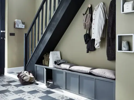 Escalier moderne avec une couleur tendance, banc de rangement gris, porte d'entrée noire et sol à motifs.