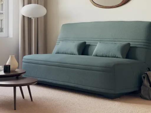 Canapé bz ou clic clac bleu canard, avec coussins, près d'une fenêtre et de tables basses. Parfait pour un petit espace.