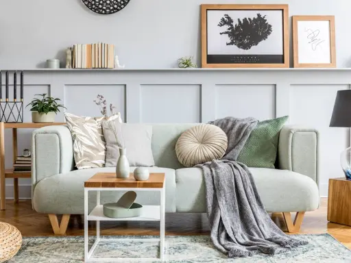 Un plaid gris drapé sur un canapé vert menthe, ajoutant une touche cosy. Idée pour comment mettre un plaid sur un canapé avec style.