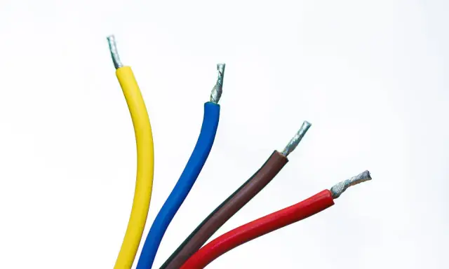 Faisceau de fils électriques colorés : jaune, bleu, marron et rouge. Un fil noir est caché parmi eux, prêt à transporter l'électricité.